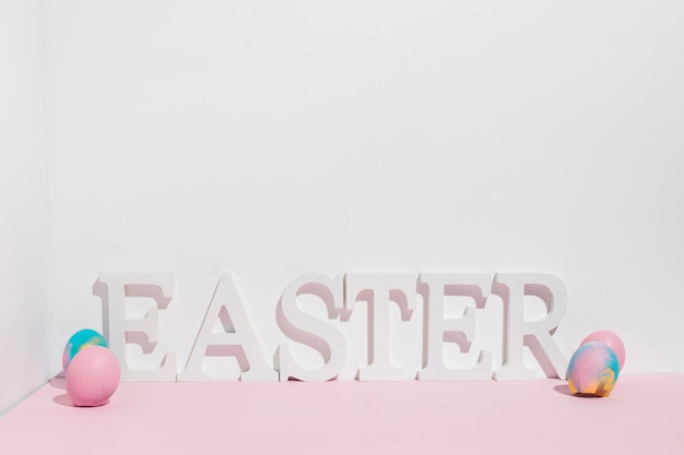 Easter inscription with colorful eggs on table