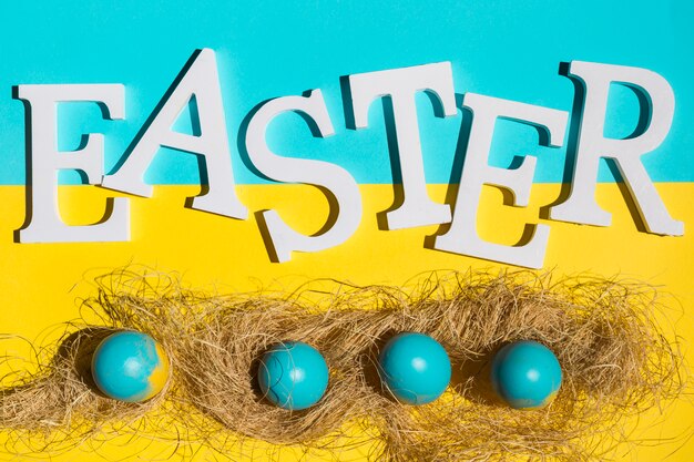 Easter inscription with colourful eggs with hay on table