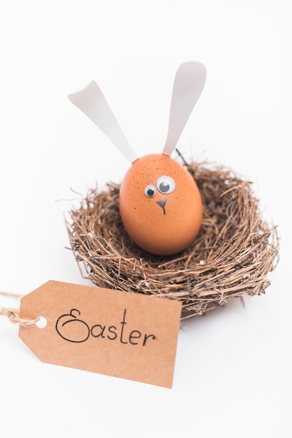 Free photo easter inscription with egg with bunny ears in nest