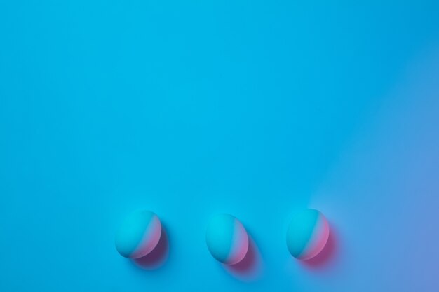 Easter traditions, pink-blue colored eggs on blue background, neon light