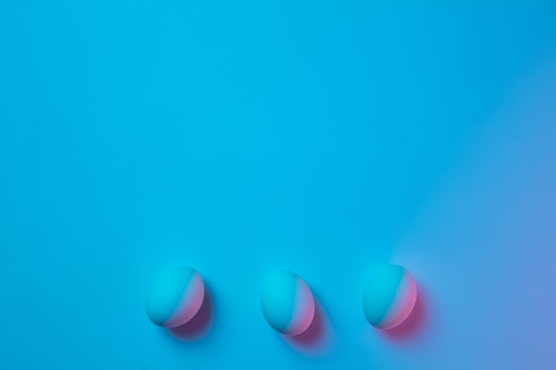 Easter traditions, pink-blue colored eggs on blue background, neon light