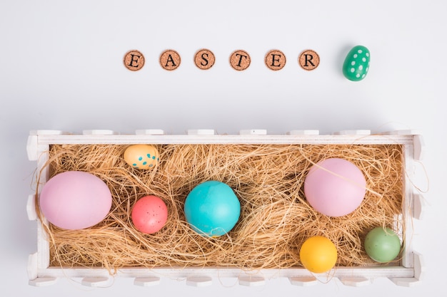 Easter word near eggs between hay in box