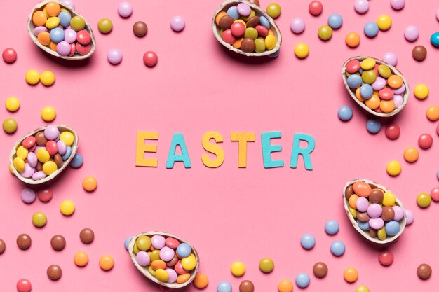 Easter word surrounded with colorful gem candies and easter eggs on pink background