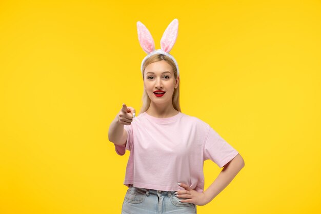 Easter young cute pretty girl with bunny ears pointing front and smiling