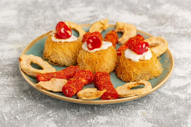 eastern pastry cookies inside green plate with white cream dried fruits and little confitures