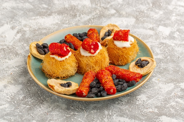 eastern pastry cookies inside green plate with white cream dried fruits and little confitures