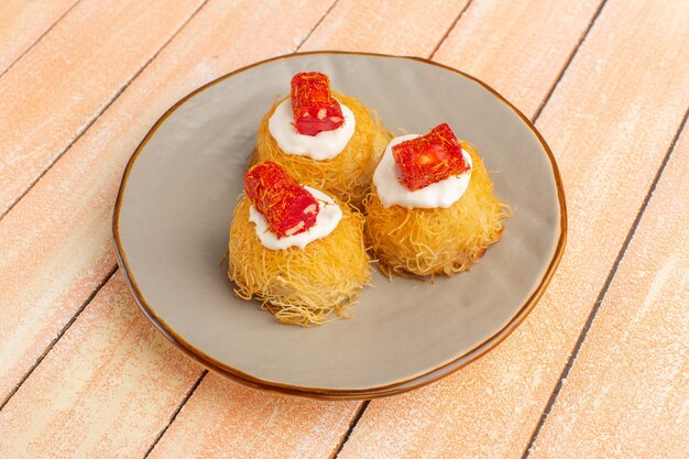 Free photo eastern pastry cookies inside plate with white cream on wood