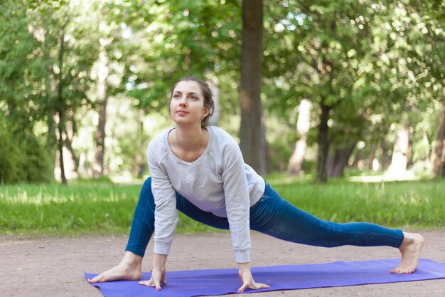 Easy variation of Lizard yoga pose in park alley