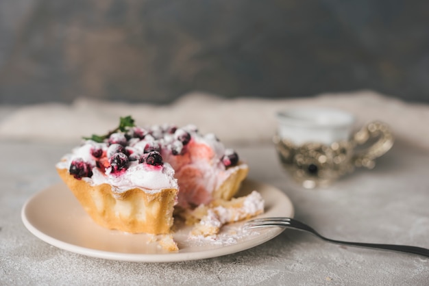 Free photo eaten berries tart on ceramics plate with stainless fork