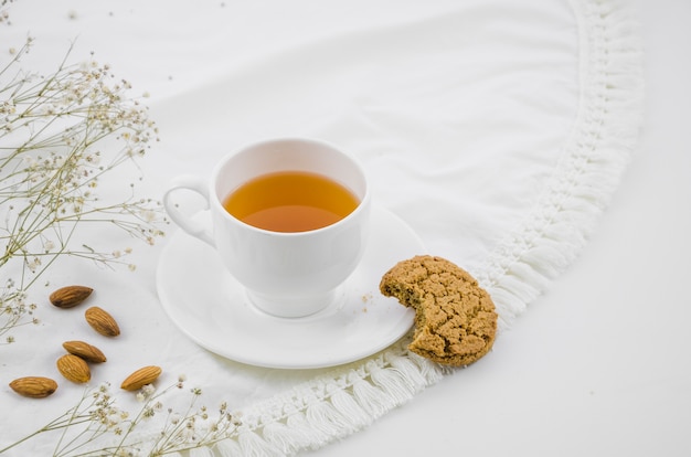 Eaten cookies and almonds with white herbal tea cup on tablecloth