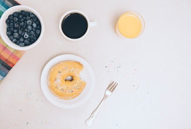 Eaten donut; coffee; juice and blueberries isolated on white background