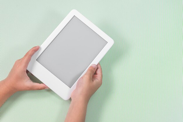 Ebook reader over green background  being held by the hand of a child