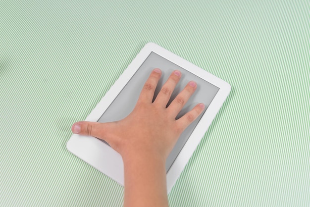 Foto gratuita lettore di ebook su sfondo verde tenuto dalla mano di un bambino