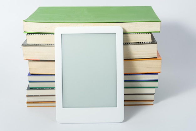 Бесплатное фото Читатель электронных книг рядом с бумажными книгами