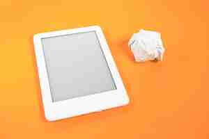 Free photo ebook reader over yellow background with paper ball beside