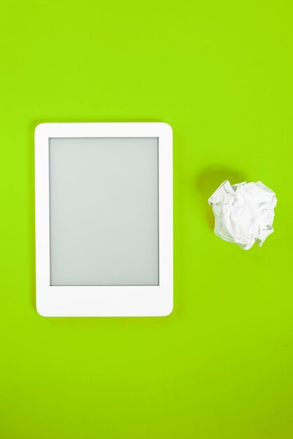 Ebook reader over yellow background with paper ball beside