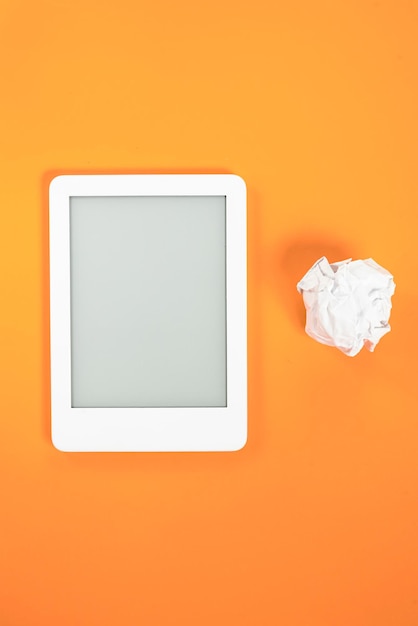 Ebook reader over yellow background with paper ball beside