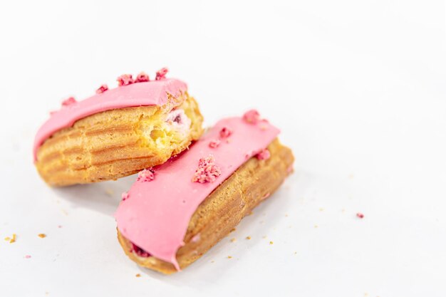 Eclair in pink glaze on a white background isolated