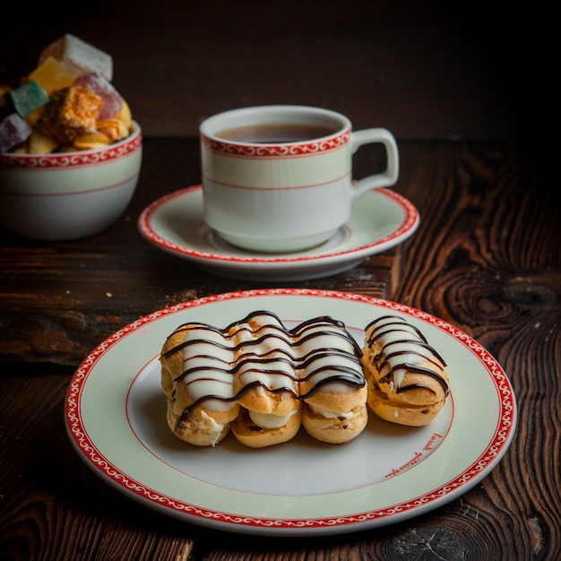 Foto gratuita eclair con una tazza di tè e zucchero nel piatto