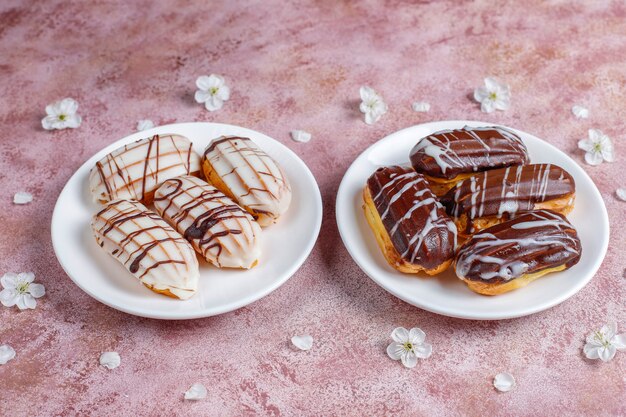 Eclairs or profiteroles with black chocolate and white chocolate with custard inside,traditional french dessert.top view.