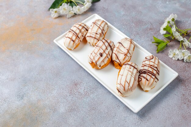 Eclairs or profiteroles with black chocolate and white chocolate with custard inside, traditional french dessert.