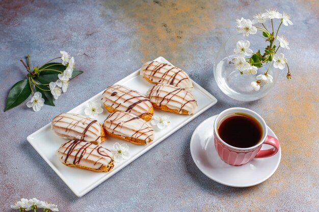 Eclairs or profiteroles with black chocolate and white chocolate with custard inside, traditional french dessert.