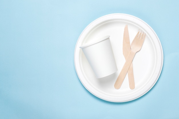 Eco-friendly disposable utensils made of bamboo wood and paper on a blue