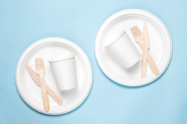 Eco-friendly disposable utensils made of bamboo wood and paper on a blue