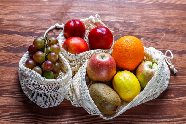 Eco-friendly simple beige cotton shopping bags for buying fruit and vegetables with summer fruits.