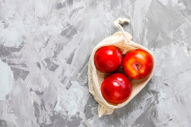 Eco-friendly simple beige cotton shopping bags for buying fruit and vegetables with summer fruits.