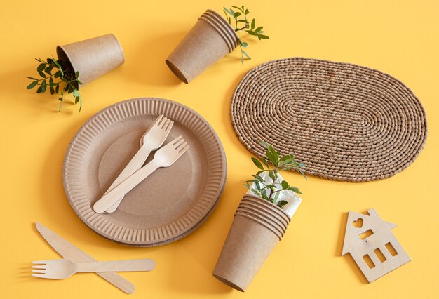 Экологичная, стильная посуда из перерабатываемой бумаги. Бумажные коробки для еды, тарелки и столовые приборы из кукурузного крахмала на оранжевом фоне.