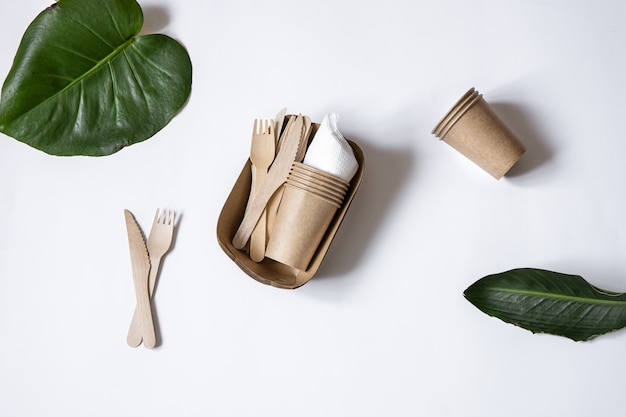 Ecological disposable tableware made of bamboo wood and paper. Cups, knives and forks isolated top view.