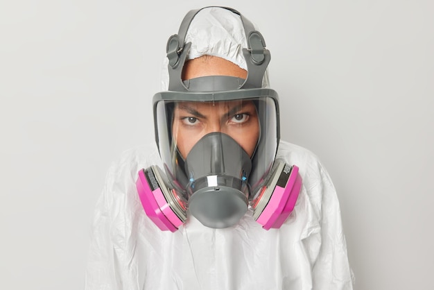 생태학적 문제 개념 화난 여성은 회색 배경 위에 격리된 공기로 독성 가스가 배출되는 것을 방지하기 위해 후드와 호흡기 마스크가 있는 보호복을 입고 자연을 보호합니다