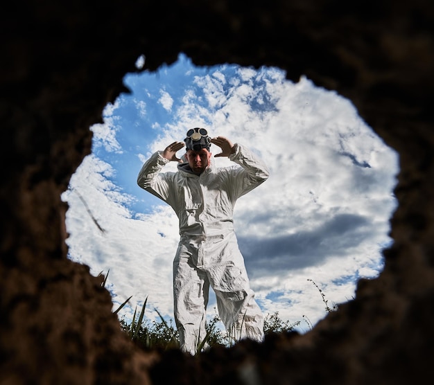 Ecologist digging pit by shovel and planting tree in polluted area