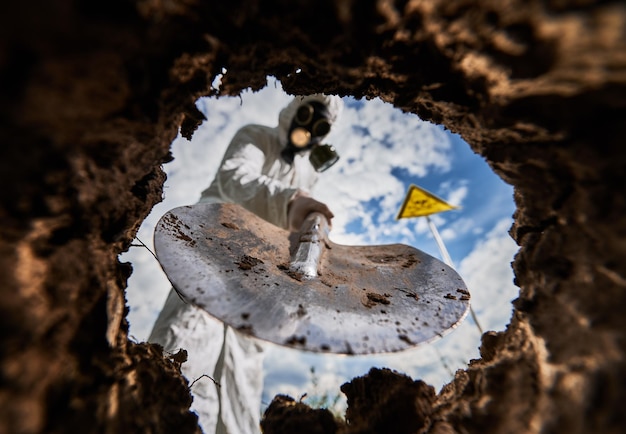 Эколог копает яму лопатой и сажает дерево в загрязненном районе