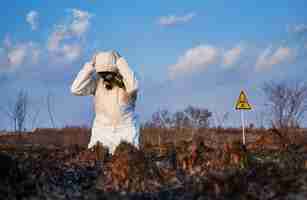 Free photo ecologist standing on his knees in field with burnt grass