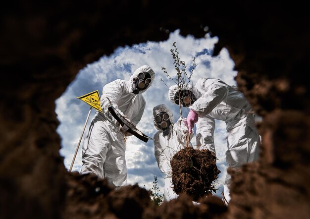 Экологи копают яму лопатой и сажают дерево в загрязненном районе