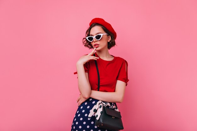 Ecstatic french lady with short haircut posing. Confident european female model in red t-shirt standing.