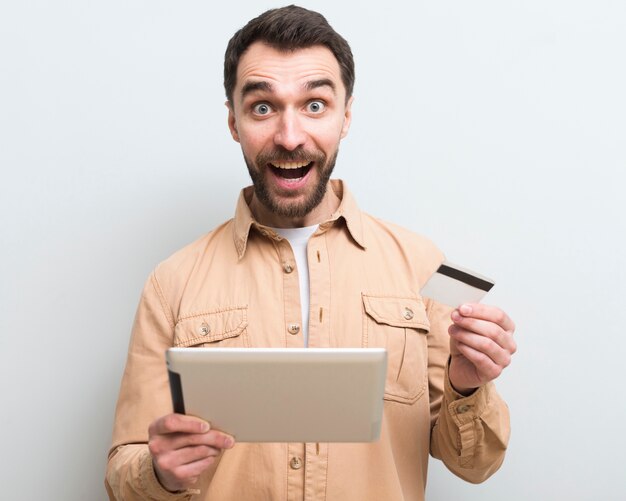 Ecstatic man holding tablet and credit card