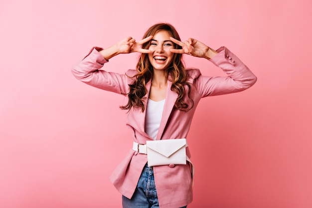 Foto gratuita ragazza dai capelli rossi estatica divertente in posa con il segno di pace. donna europea accattivante che si rilassa durante il servizio di ritratti al coperto.