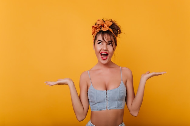 Ecstatic sensual girl standing with surprised smile and posing with hands up