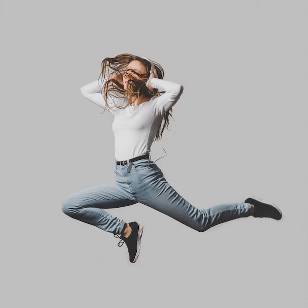 Free photo ecstatic woman with headphones jumping in the air