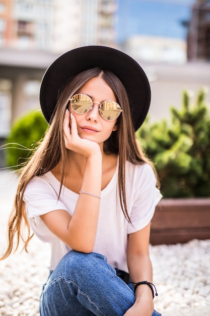 Ecstatic young woman in hat outdoors sitting on the bench