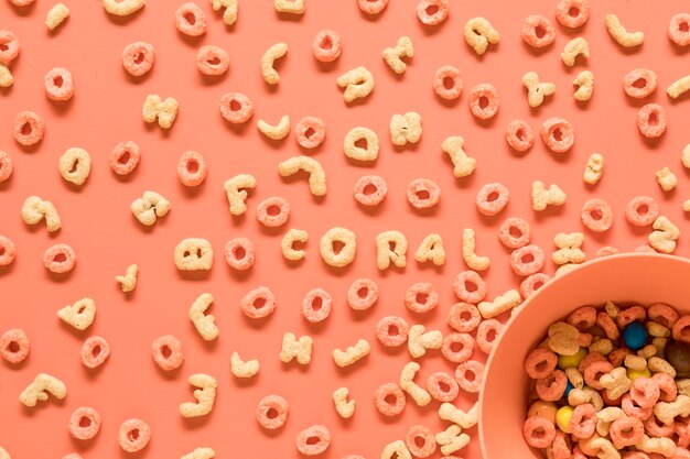 Edible letters of alphabet and bowl on orange background