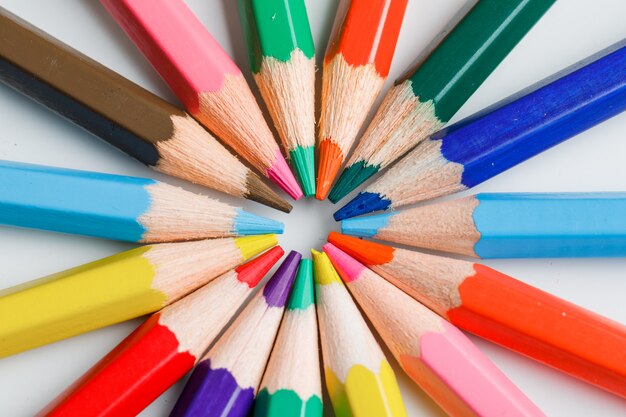 Концепция образования с цветными карандашами на белом.