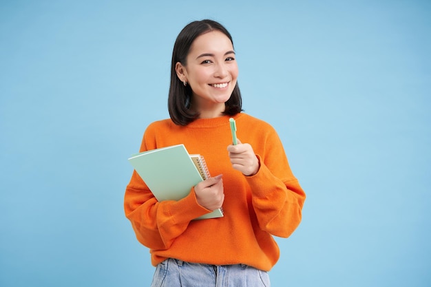 Free photo education and students happy asian woman holding notebooks and laughing smiling at camera enjoys goi