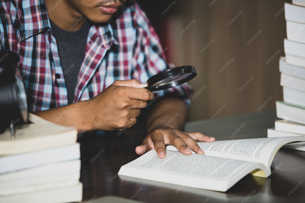 a close-up student looking through a magnifying glass to read a page of a book