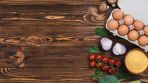 Free photo egg carton; mushroom; polenta; onion and broccoli on wooden desk