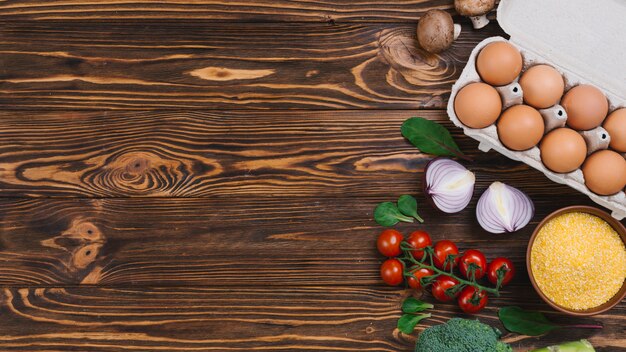 Egg carton; mushroom; polenta; onion and broccoli on wooden desk