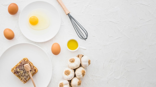 Egg carton; yolk; garlic braid; honeycomb and whisker on white textured backdrop